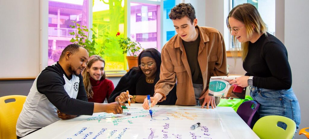 Groupe de 5 étudiants autour d'une table dans la classe d'éducation à l'enfance