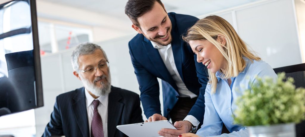 Photo de 2 hommes et une femme dans un bureau qui regardent une tablette