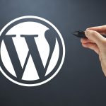 Logo WordPress avec une main qui tient un stylet