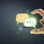 Gros plan sur une main qui tient deux bulles de conversation