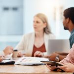Trois femmes et deux hommes autour d'une table de conférence