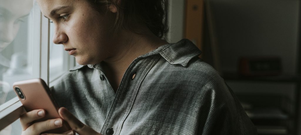Une jeune fille regarde tristement par la fenêtre