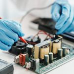Deux mains gantées font une soudure sur une pièce életronique