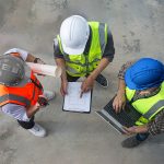 Trois hommes avec des casques de sécurité sur un chantier