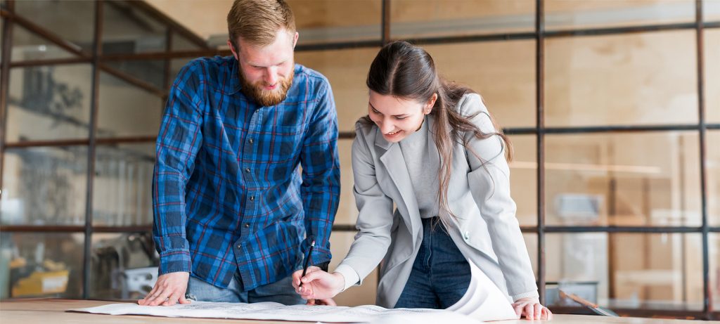 Un homme et une femme penchés au dessus d'un plan