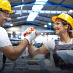 Deux personnes dans une usine avec des casques jaunes. à gauche le logo Performance 360 - Améliorer votre productivité