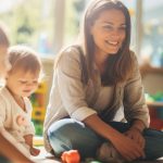 Une éducatrice entourée de 3 jeunes enfants dans une salle de jeu