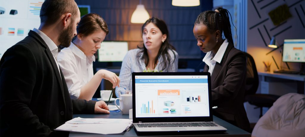 Quatre personnes à une table avec un ordinateur portable et des feuilles de papier