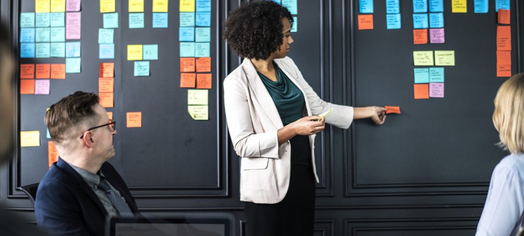 Une dame devant un mur couvert de post-it