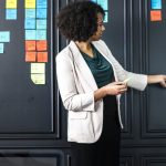 Une dame devant un mur couvert de post-it