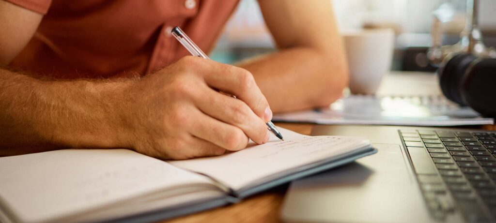 Une personne a son bureau qui écrit dans un carnet de note