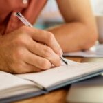 Une personne a son bureau qui écrit dans un carnet de note