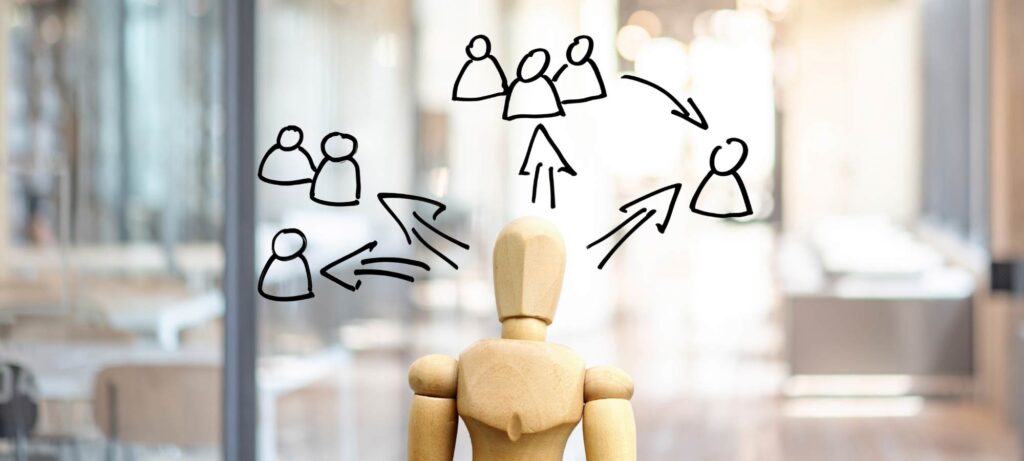 Un personnage en bois pensant déléguer à des personnes et groupe de personnes
